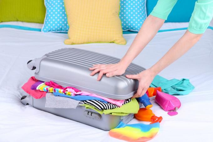 Tyttö kerää matkalaukku sängyllä lähikuva